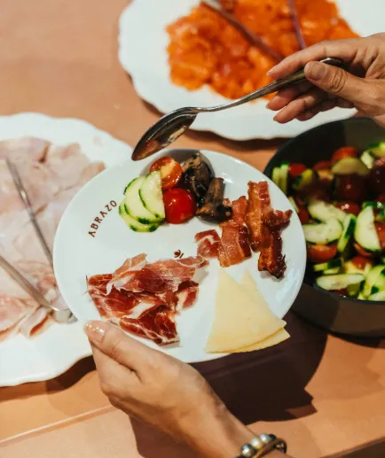 Plan on a plate of charcuterie, cheese and various vegetables served at a buffet