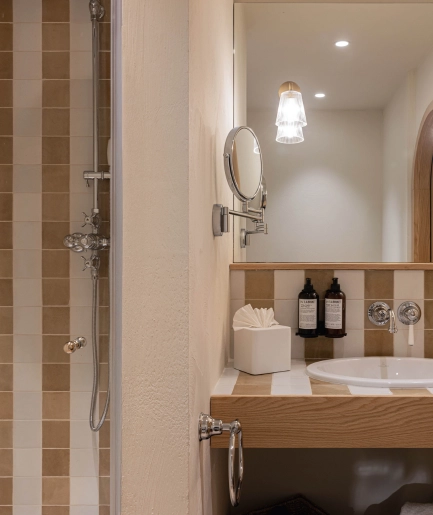 Salle de bain moderne : un lavabo ovale et encastré repose sur un comptoir à motifs à carreaux. La douche à l'italienne est carrelée de larges rayures verticales marron clair et blanc, avec une pomme de douche à effet pluie