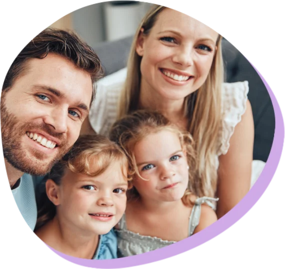 Lächelnde Eltern mit zwei kleinen Töchtern, die zusammen für ein Familienfoto posieren.
