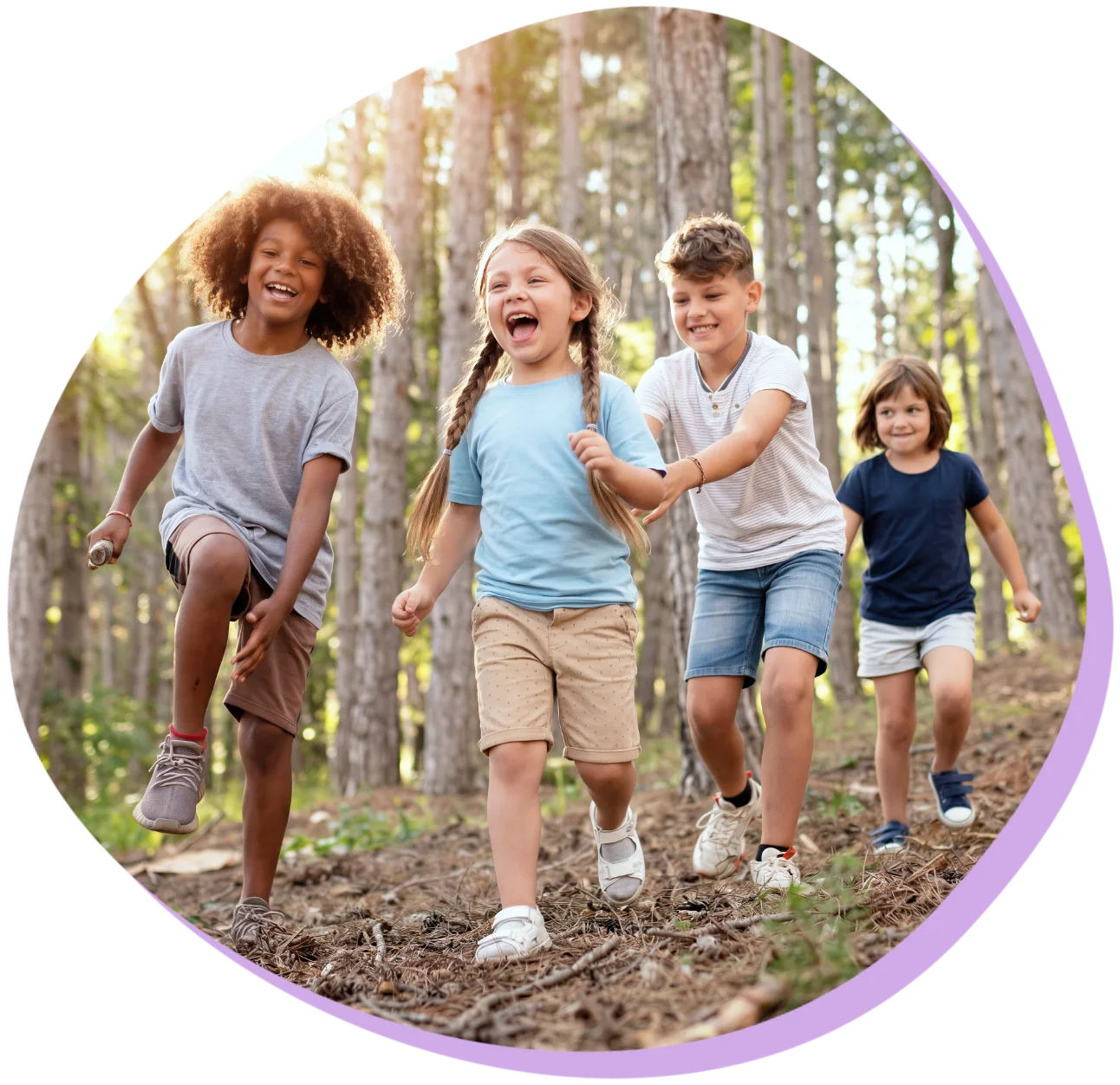 Vier lachende Kinder laufen im Wald, umgeben von hohen Bäumen und Sonnenlicht.