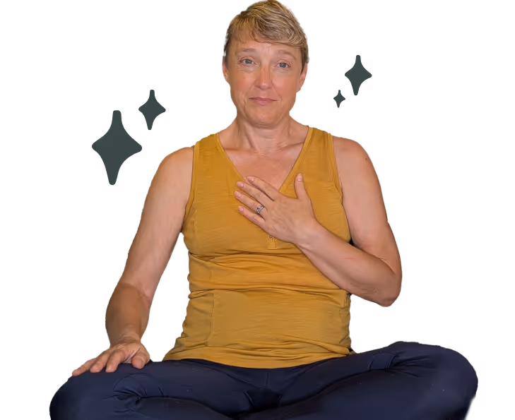 Woman sitting cross-legged with one hand on her chest in a calm, mindful posture.