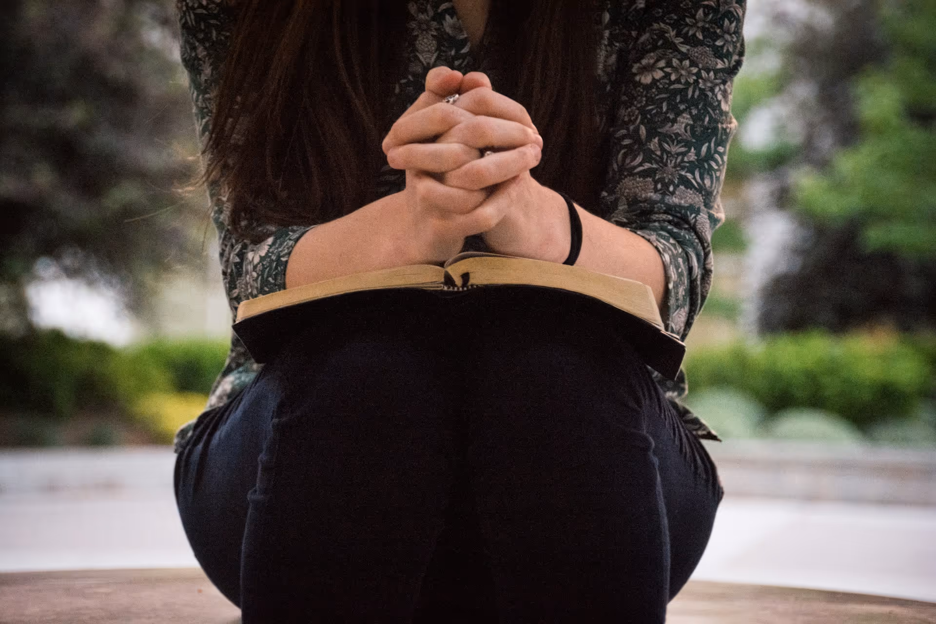 Young woman praying with an open Bible on her lap
