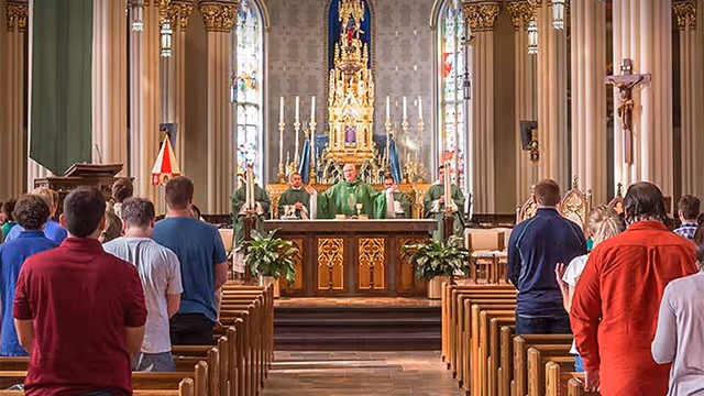 Priest holding his arms out behind the altar during mass