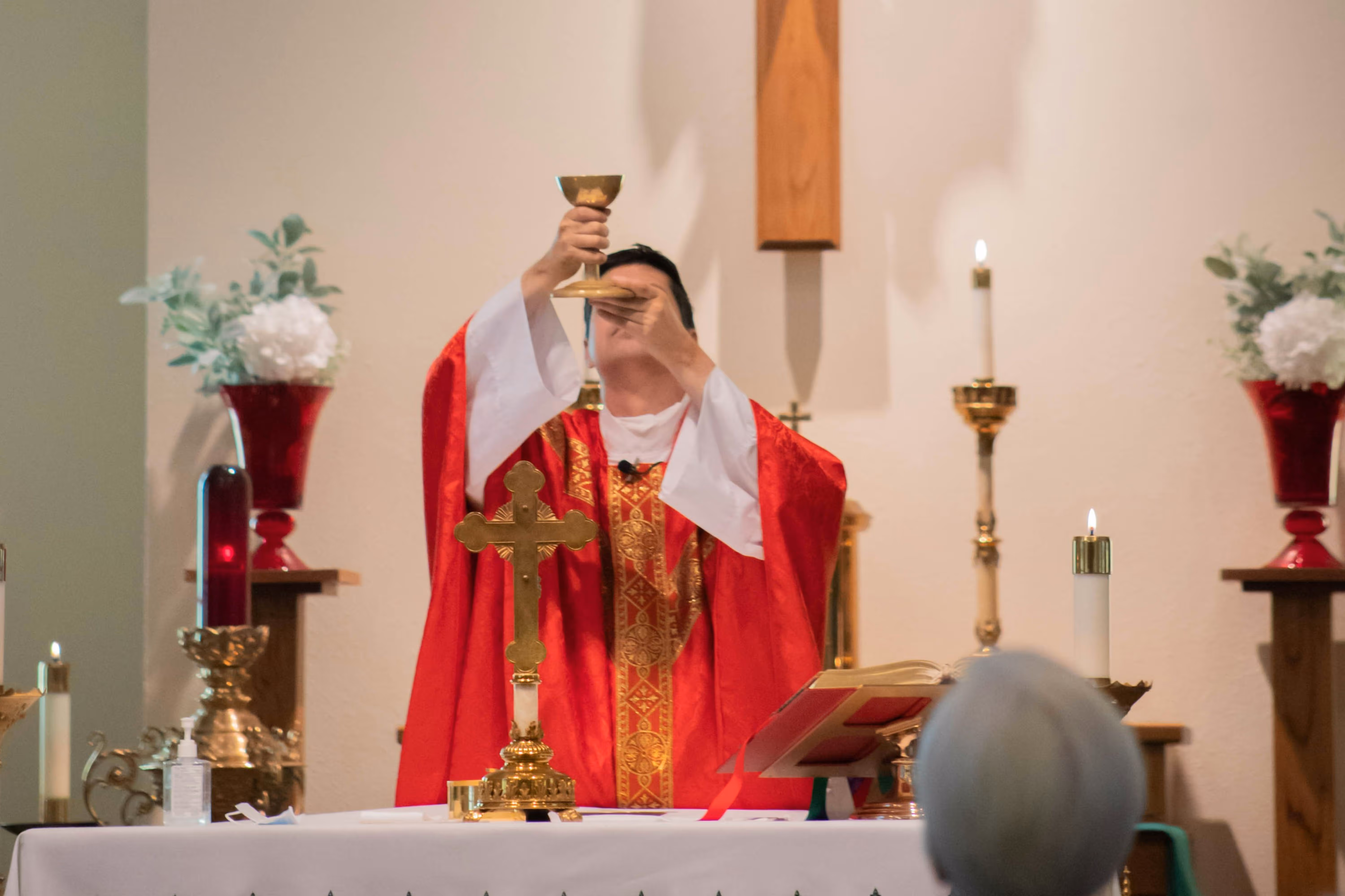 Catholic priest raising the chalice over the altar during the Consecration at Mass