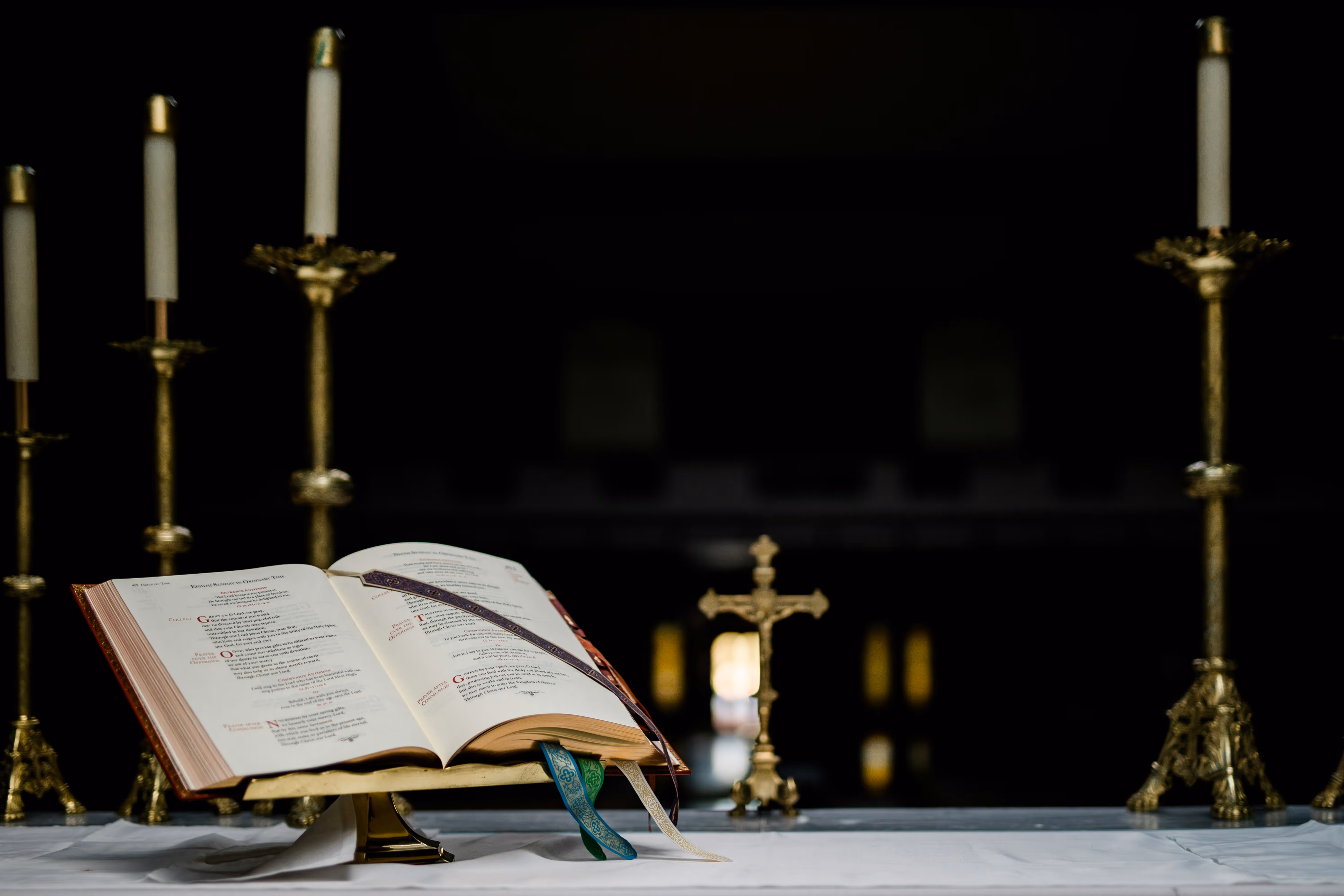Open Roman Missal on an altar with a golden crucifix and candlesticks