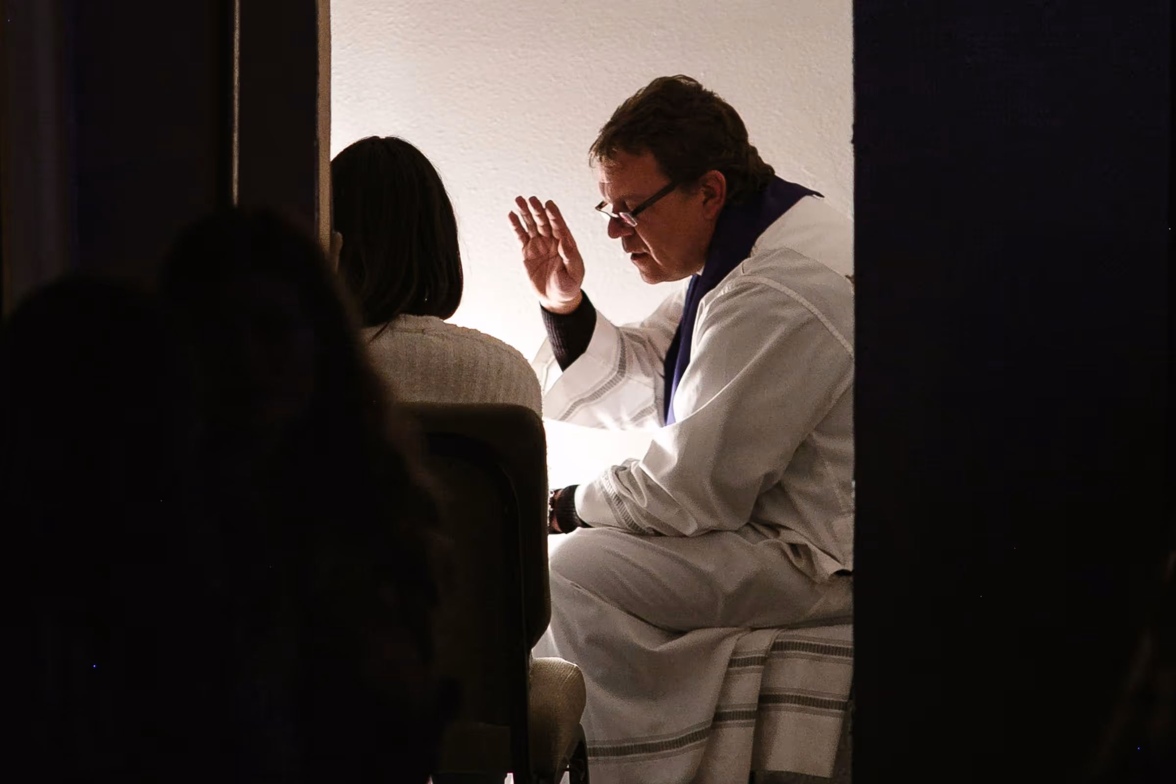 Catholic priest hearing a penitent's confession and giving absolution