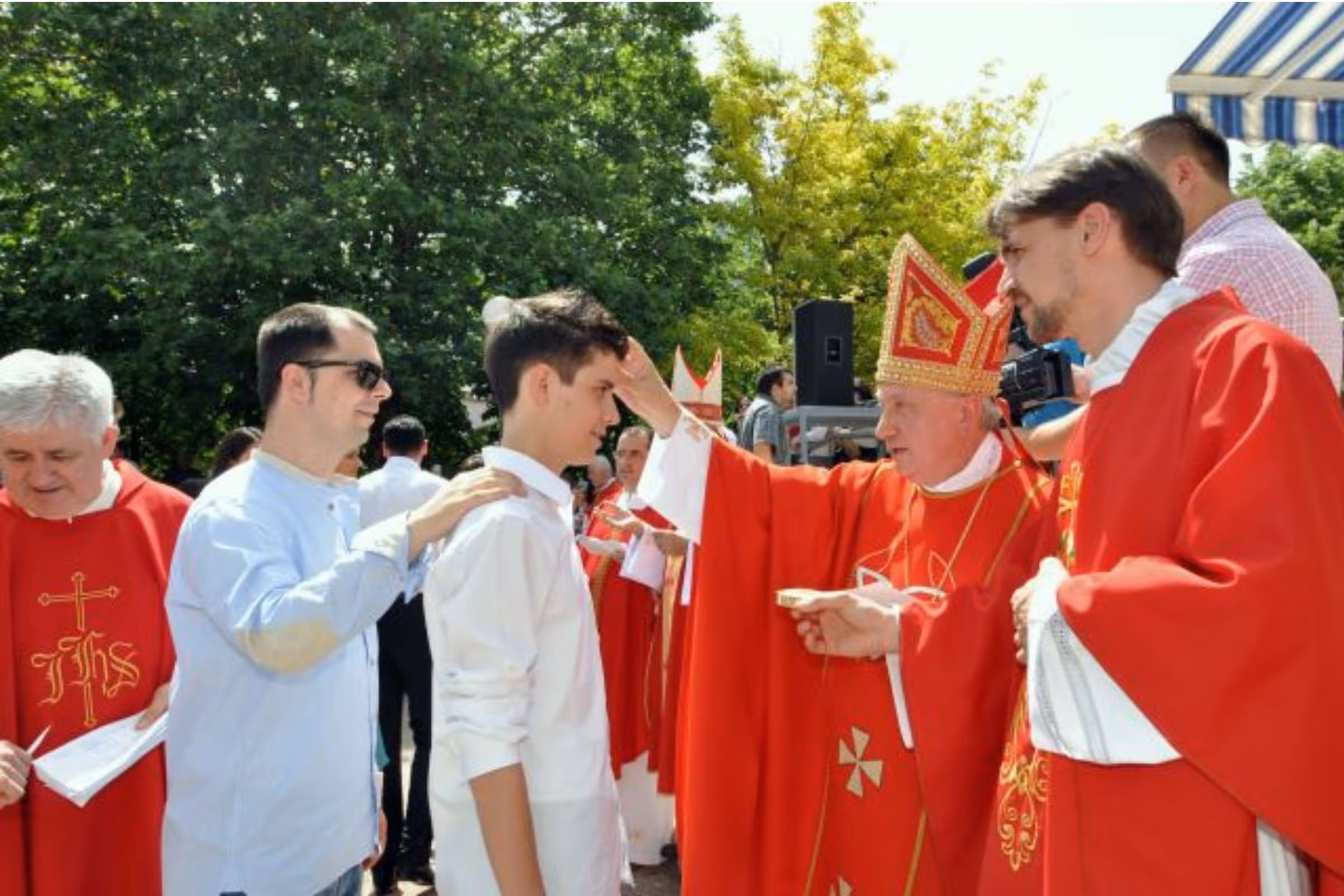 Teenage boy receiving the Sacrament of Confirmation from a Catholic bishop