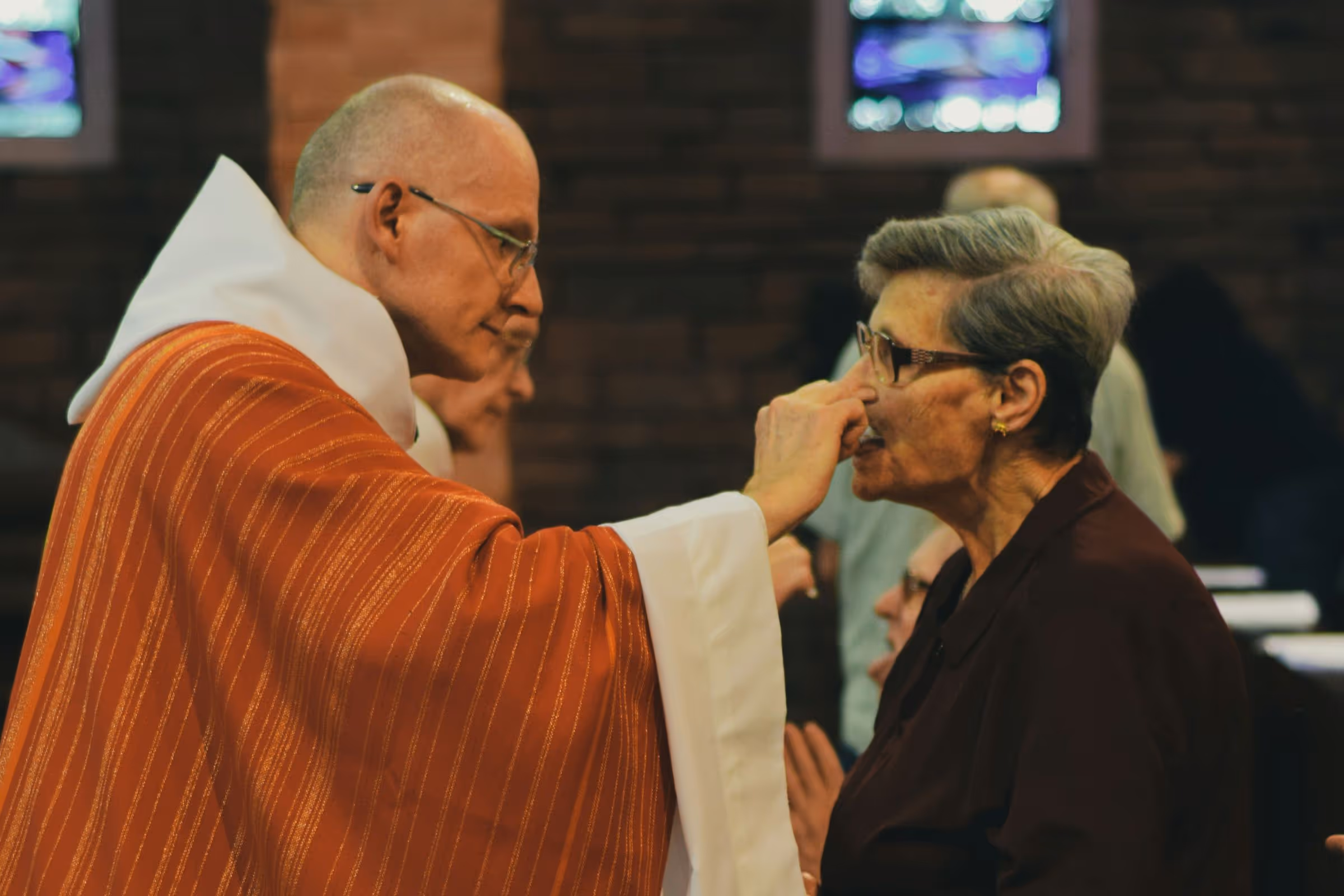 Elderly woman receiving Holy Communion from a Catholic priest