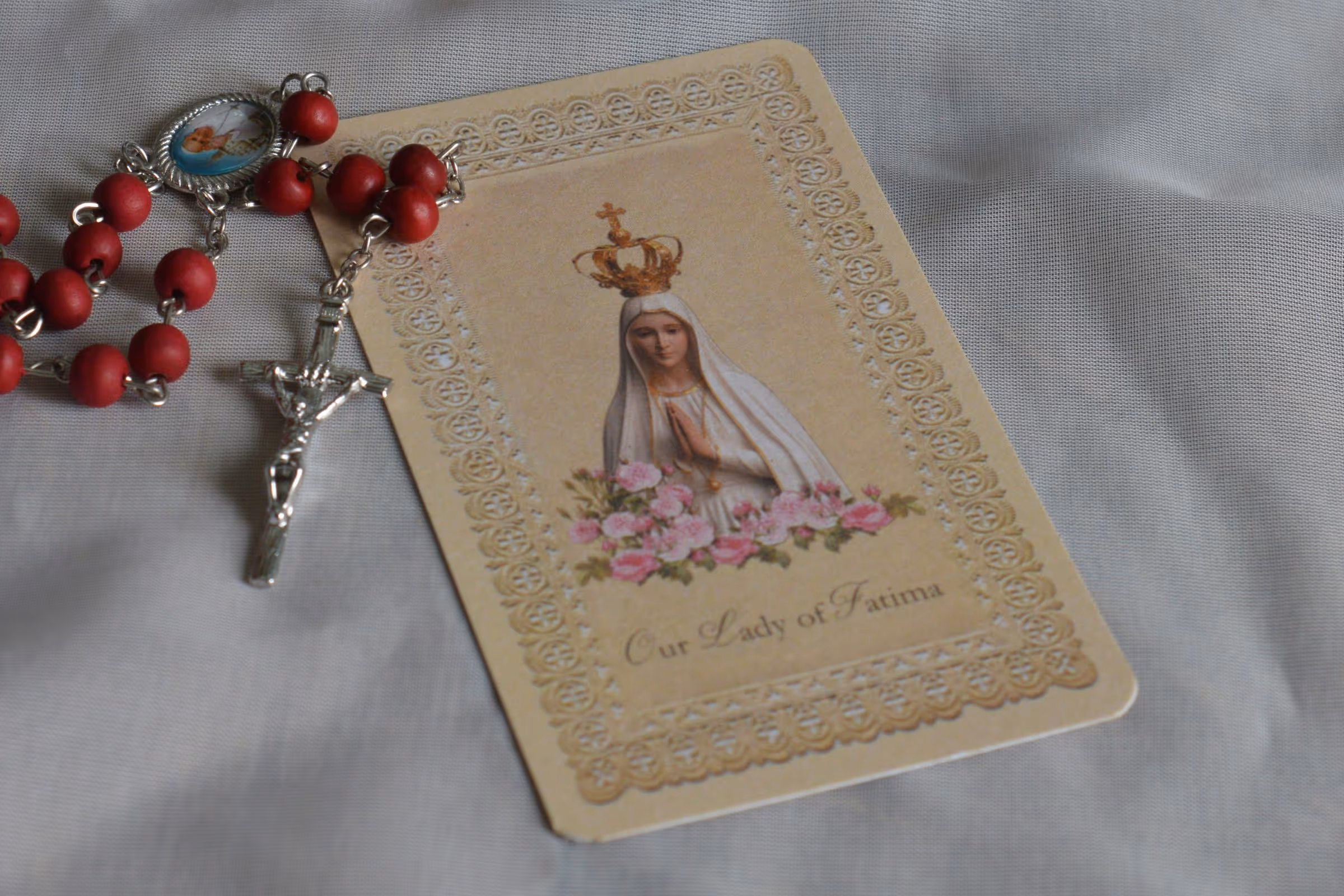Our Lady of Fatima prayer card and a red rosary