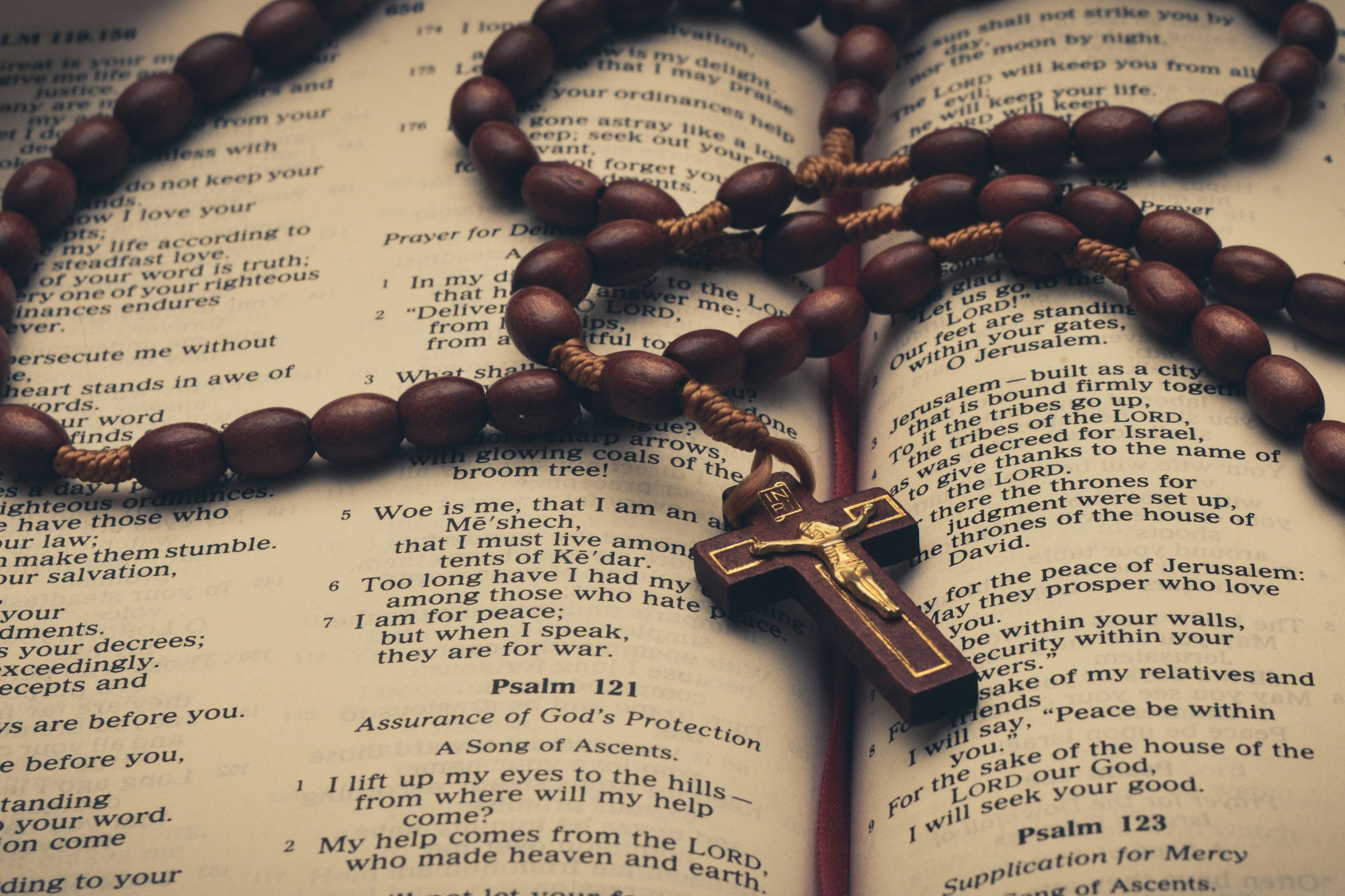 A Bible opened to the Psalms with wooden rosary beads