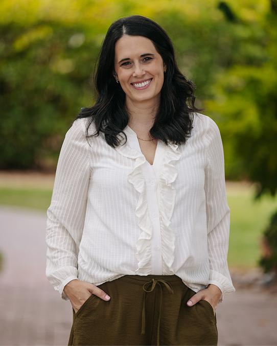 A profile photo of Amanda Nemeth in a white blouse and brown pants. 