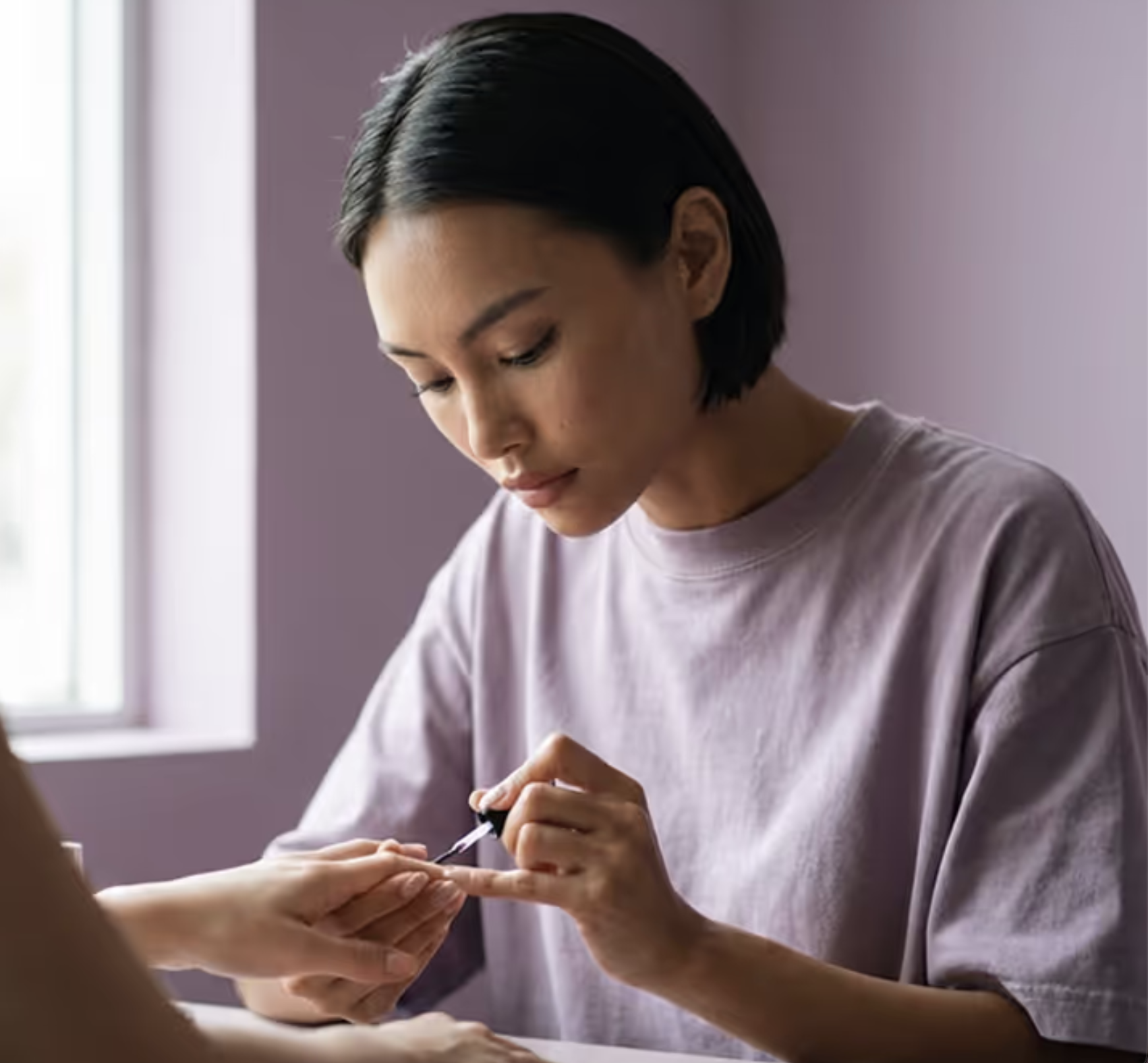 Nail artist painting a client's nails in her studio