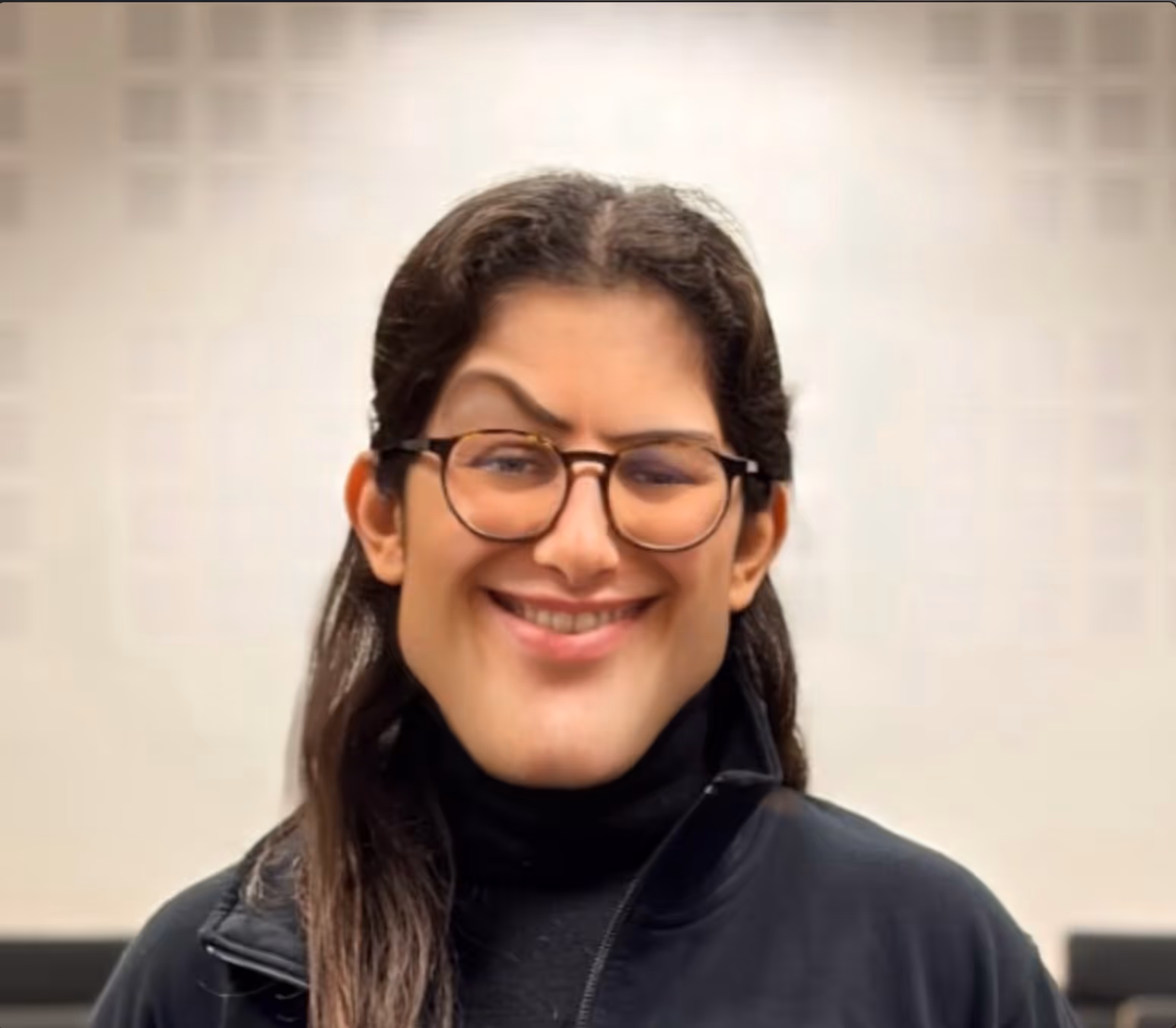 Portrait d'une personne souriante portant des lunettes et un col roulé noir
