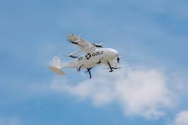 Drone blanc volant dans un ciel bleu clair avec quelques nuages