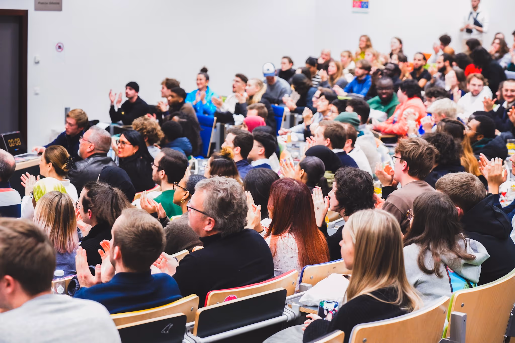 Salle de conférence pleine de personnes applaudissant lors d'un événement