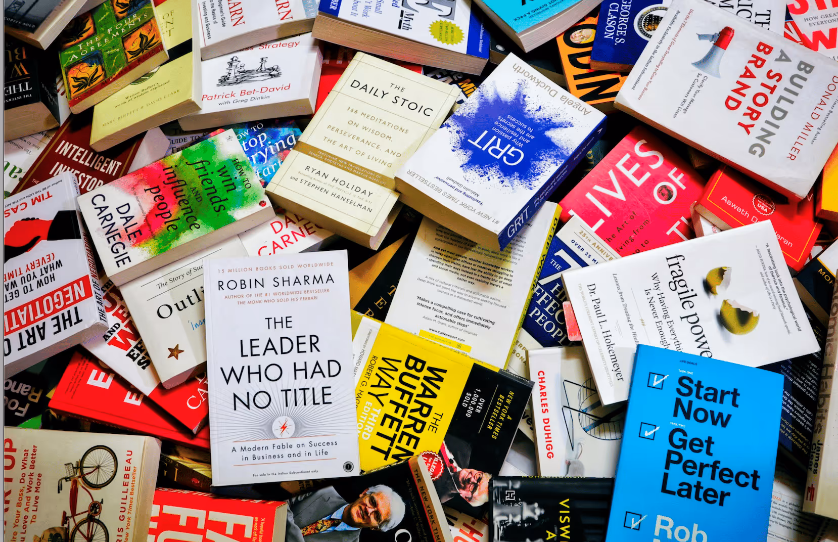 Pile de livres de développement personnel et de business, incluant des titres populaires comme «The Daily Stoic», «The Leader Who Had No Title», et «Start Now Get Perfect Later».