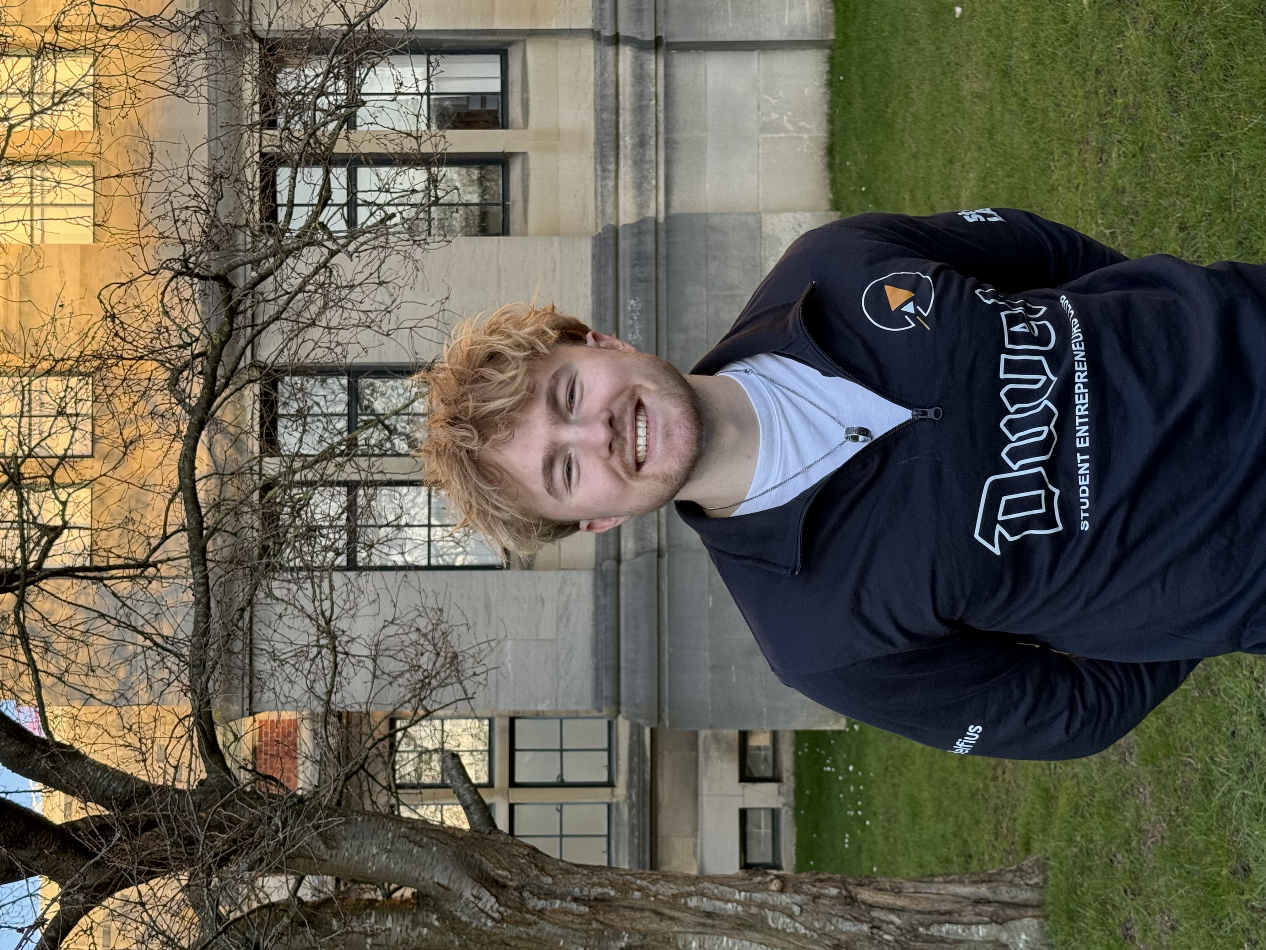 Gros plan d'un jeune homme blond avec un léger sourire.