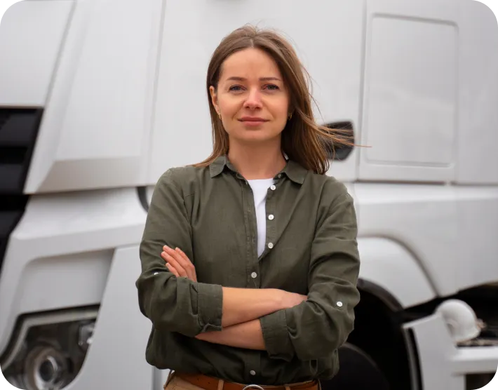 Confident woman with arms crossed standing in front of a white truck.