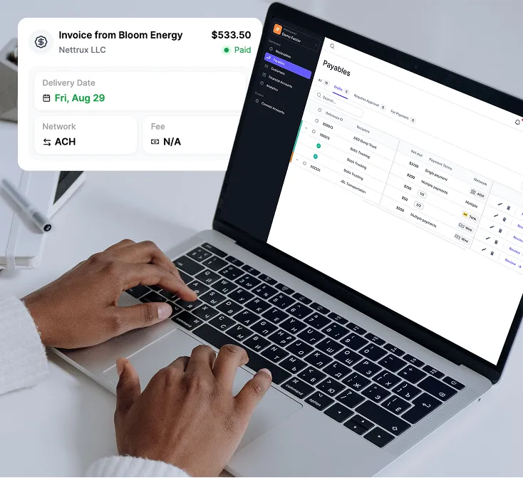 Person typing on a laptop displaying a payables management dashboard with invoice details from Bloom Energy for $533.50 marked as paid.