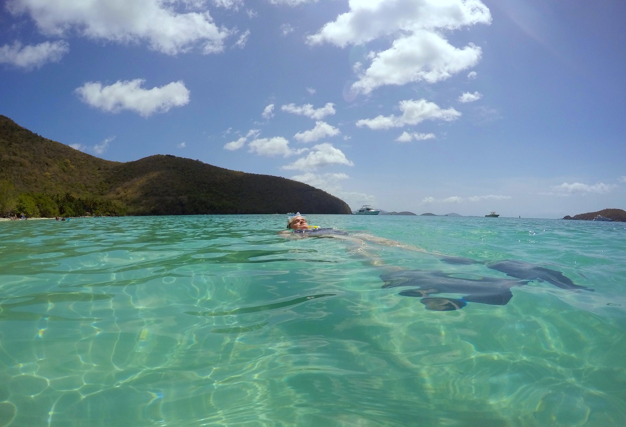 Snorkeler floating at the surface at Maho Bay Beach, St. John, with the bay's green hills visible in the background