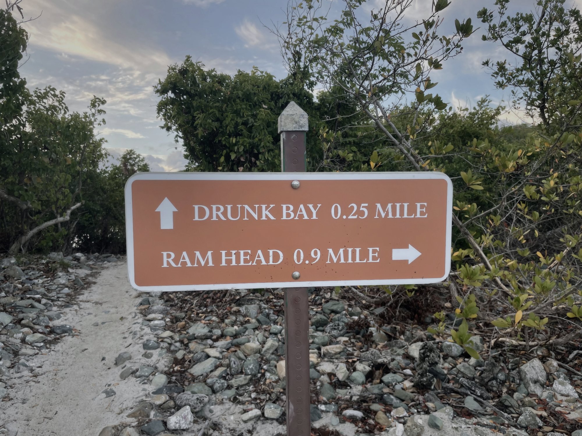 Trail junction sign at Salt Pond Bay marking distances to Drunk Bay and Ram Head