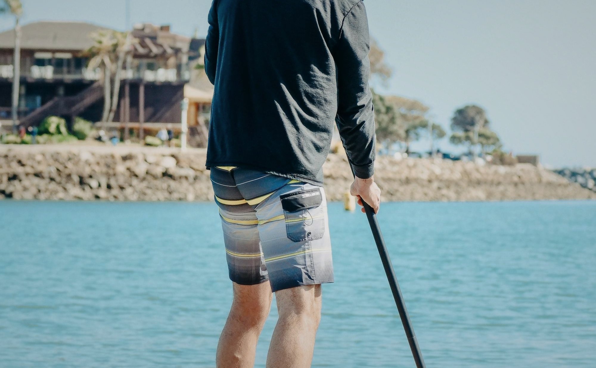 Stand-up paddleboarder on open ocean water, paddling under clear skies