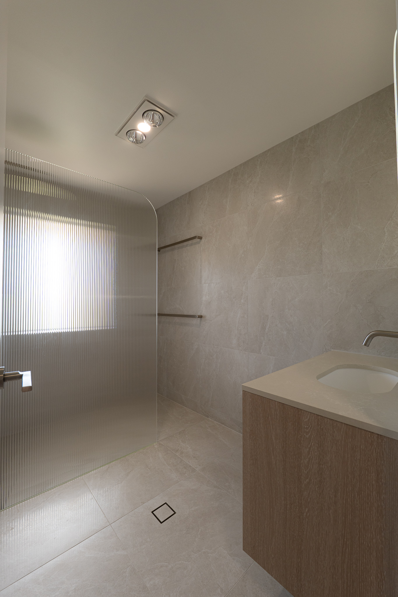 Bathroom with blue tiled floor, white double vanity with assorted toiletries, wall mirror, and an open door leading to another room with toys.