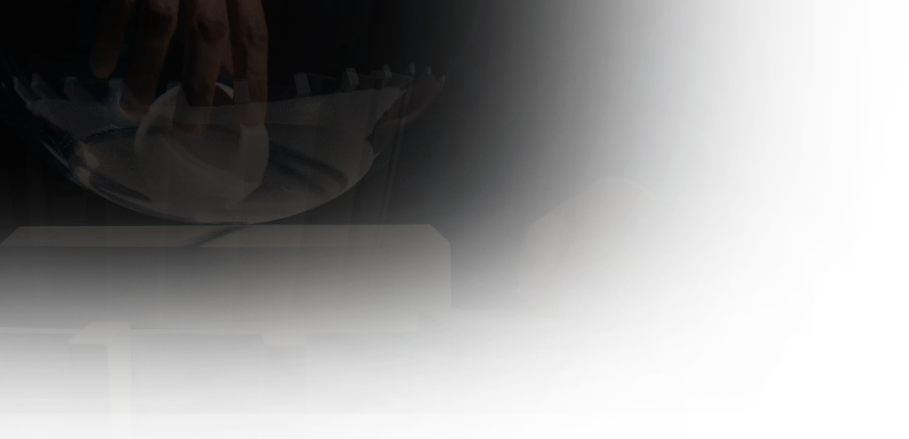Hand tipping dominos in a chain reaction with a clear sphere above them on a platform.