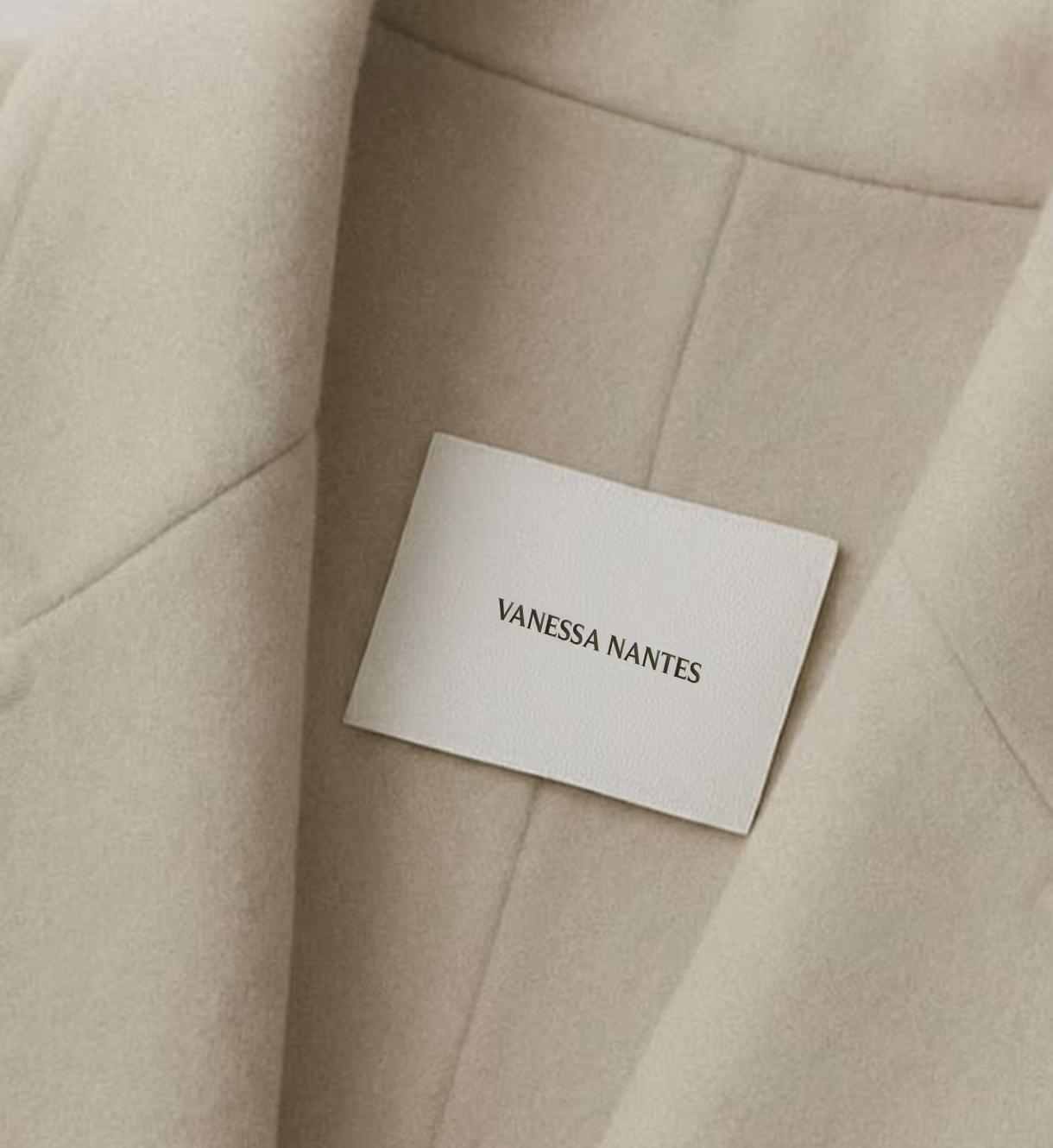 White rectangular label with the text 'VANESSA NANTES' on a beige fabric surface.