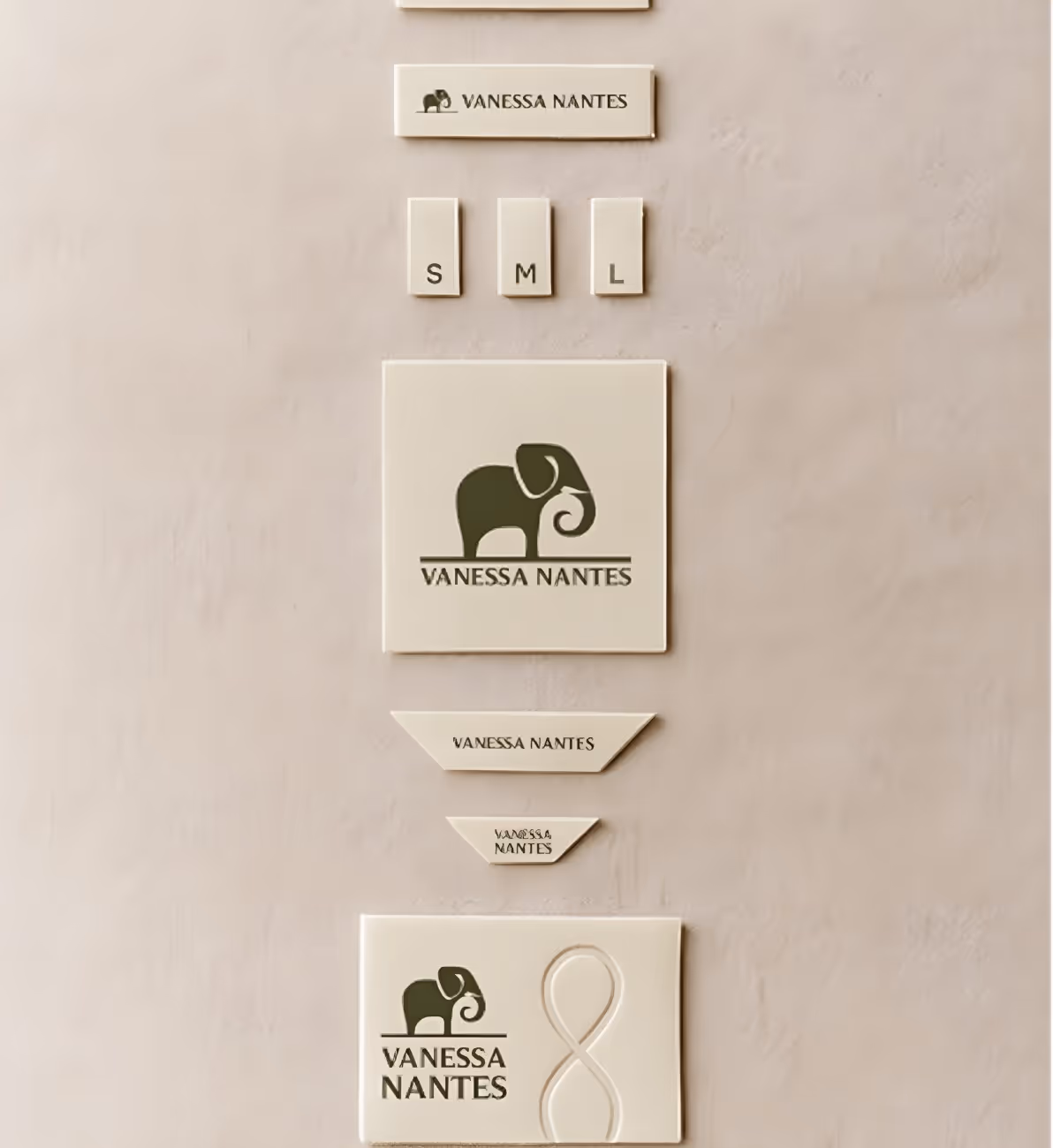 Cream-colored product labels and tags featuring a dark green elephant logo and the text 'Vanessa Nantes' in various sizes and shapes.