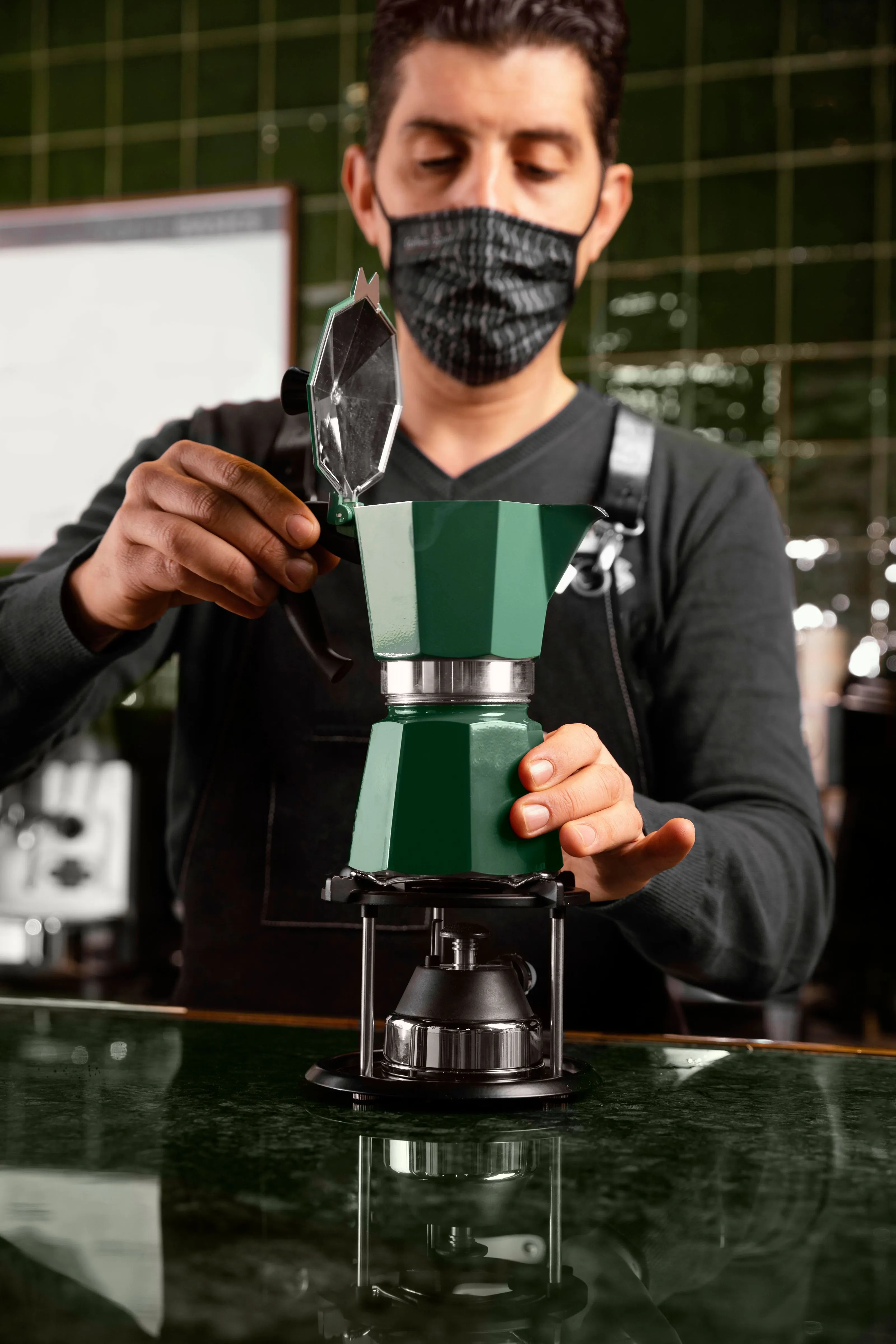Barista in mask preparing coffee with moka pot