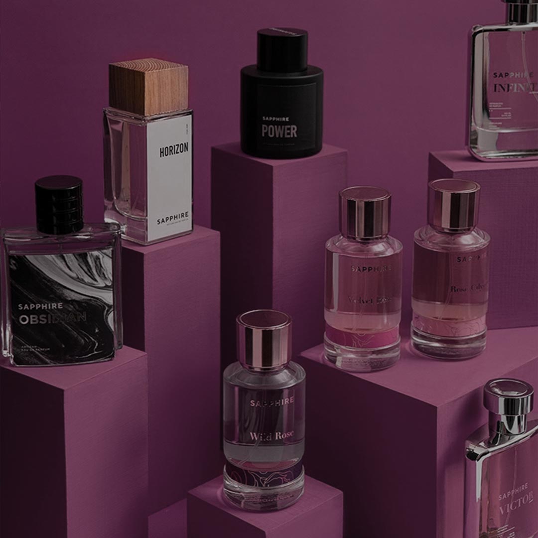 Various Sapphire brand perfume bottles arranged on purple geometric pedestals against a purple background.