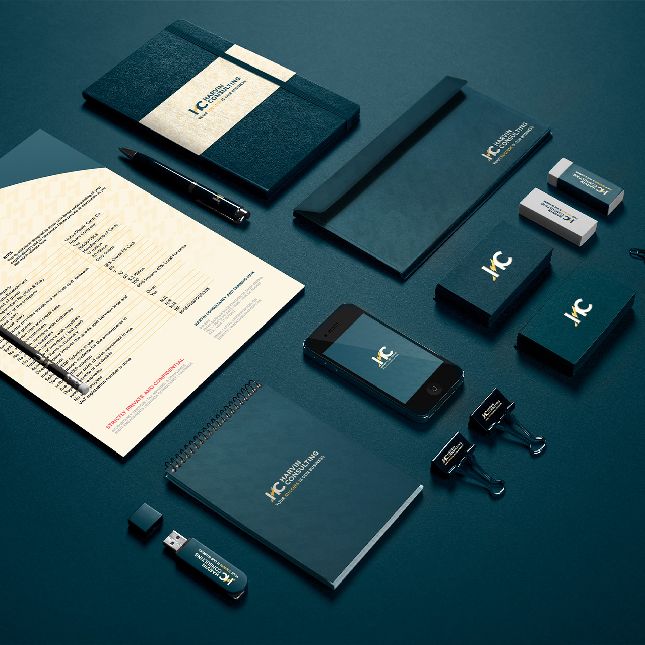 Flat lay of charcoal blue corporate branding items including notebooks, pen, smartphone, USB drive, business cards, paper, erasers, and binder clips with Harvin Consulting logo and slogan.