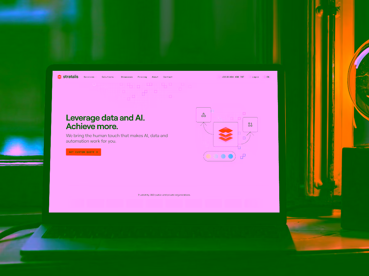 Laptop on desk displaying Stratalis website with headline 'Leverage data and AI. Achieve more.' and a custom quote button.