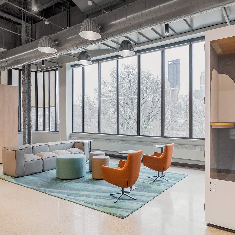 grey couch facing two organce chairs in open concept area at Nova Place