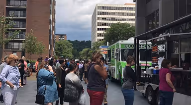 People gathering around food trucks on Nova Place campus