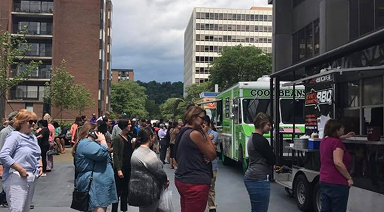 People gathering around food trucks on Nova Place campus