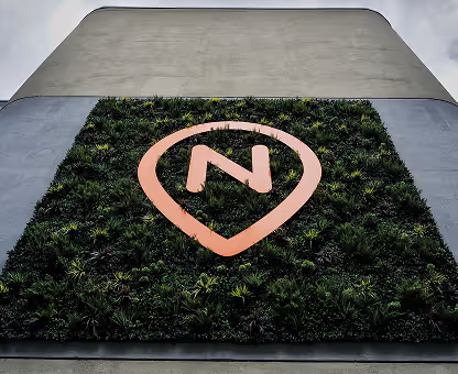 Nova Place sign surrounded by greenery on side of building