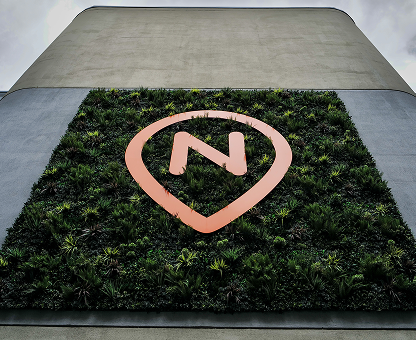 Nova Place sign surrounded by greenery on side of building