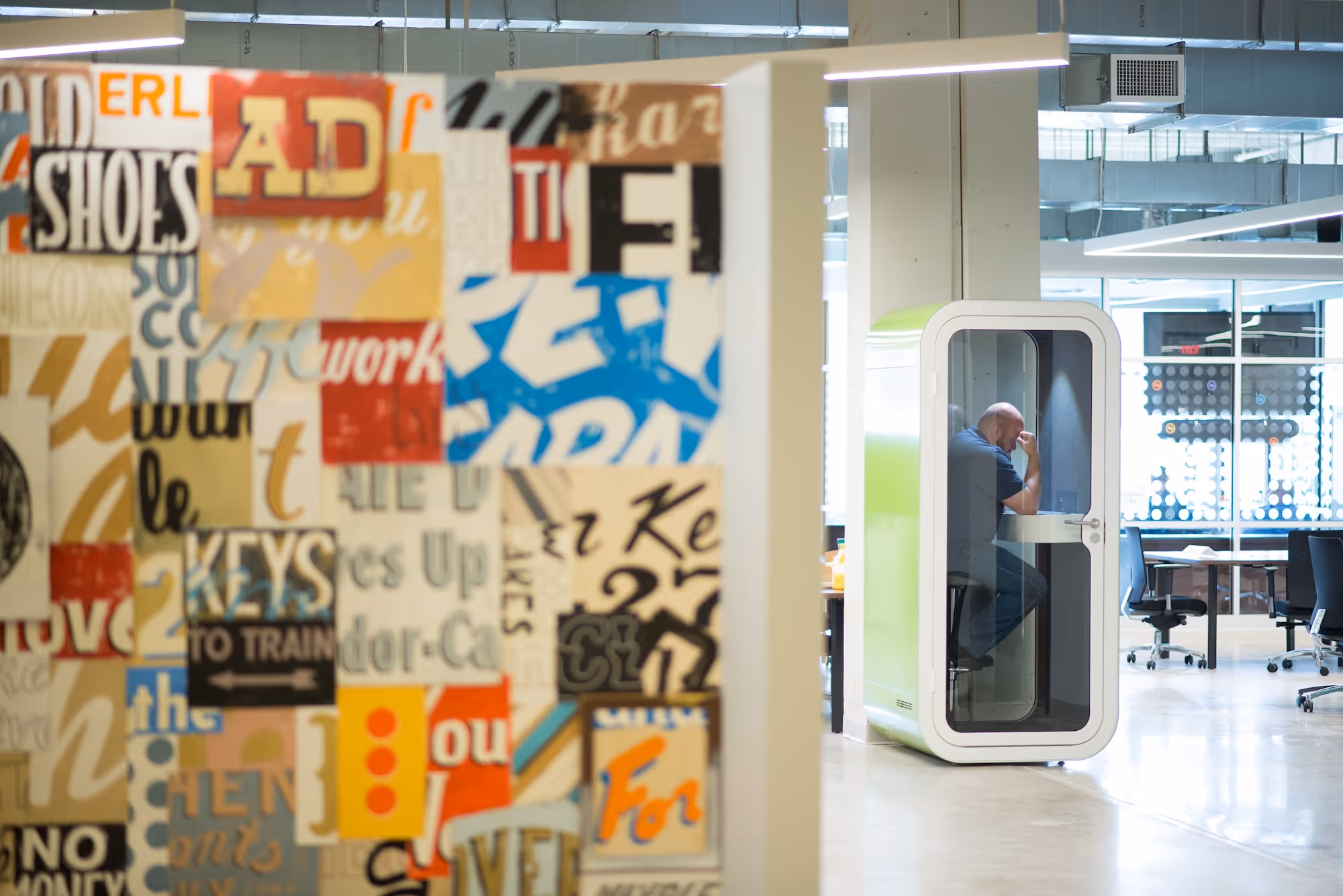 Image of artwork on the wall and a man taking a call in a Pod.