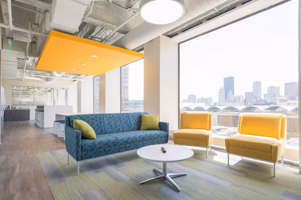 Image of seating area with modern furniture and large windows.