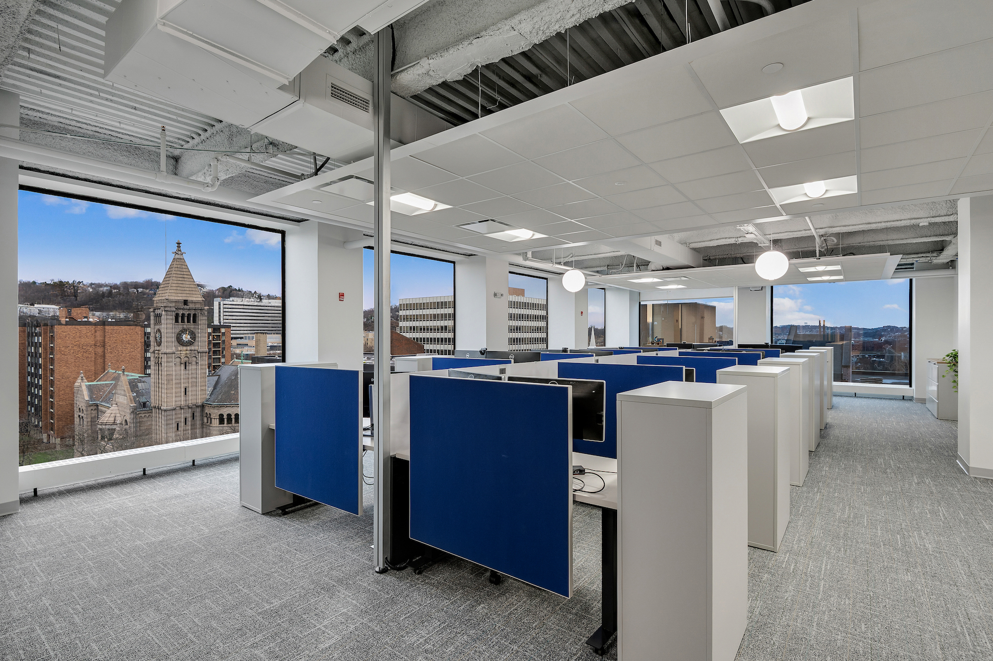 Image of a coworking environment with cubicles and large windows overlooking a cityscape