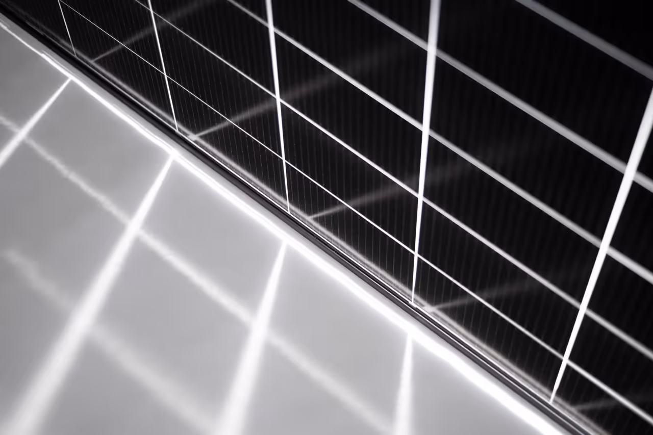 Panel solar con patrón de celosía reflejado en superficie brillante.