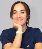 Smiling woman with dark hair resting her chin on her hand wearing a navy blue top and white smartwatch.
