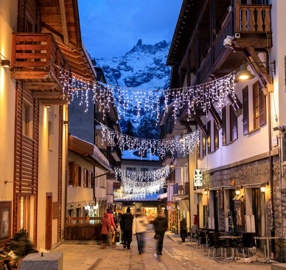 Via centrale di Courmayeur illuminata in inverno con le montagne sullo sfondo