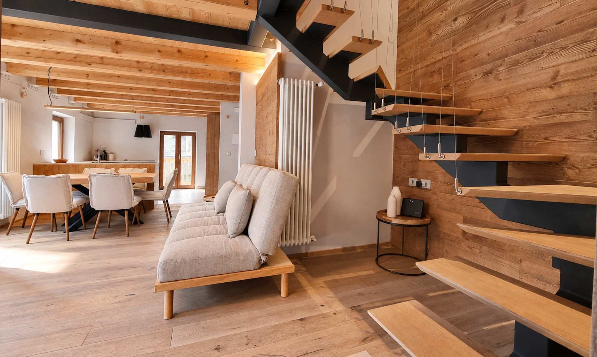 Wohnbereich mit Holzbalken und Treppe in einer Ferienwohnung in Courmayeur