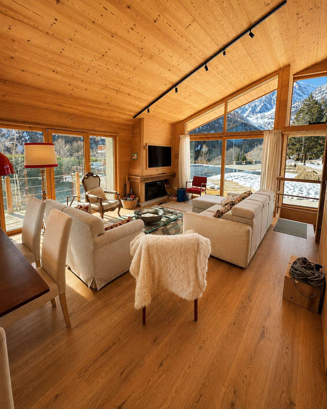 Wohnzimmer mit Holzdecke und Blick auf verschneite Berge in einer Ferienwohnung bei Courmayeur