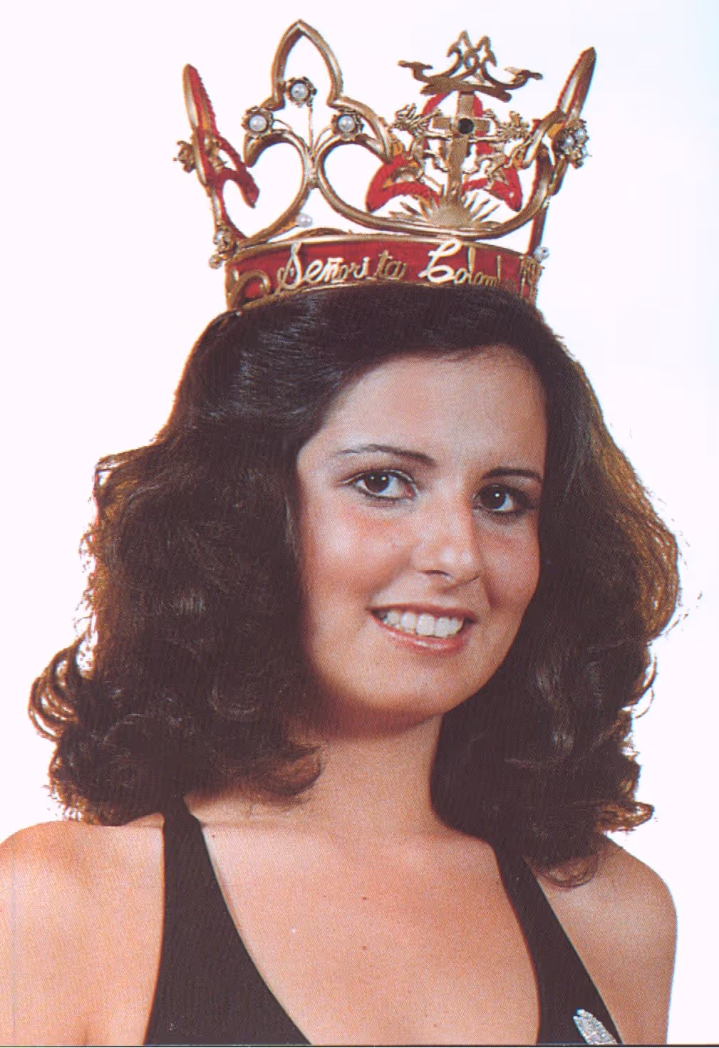Mujer joven con cabello rizado y corona de Reina Señorita Colombia, sonriendo.