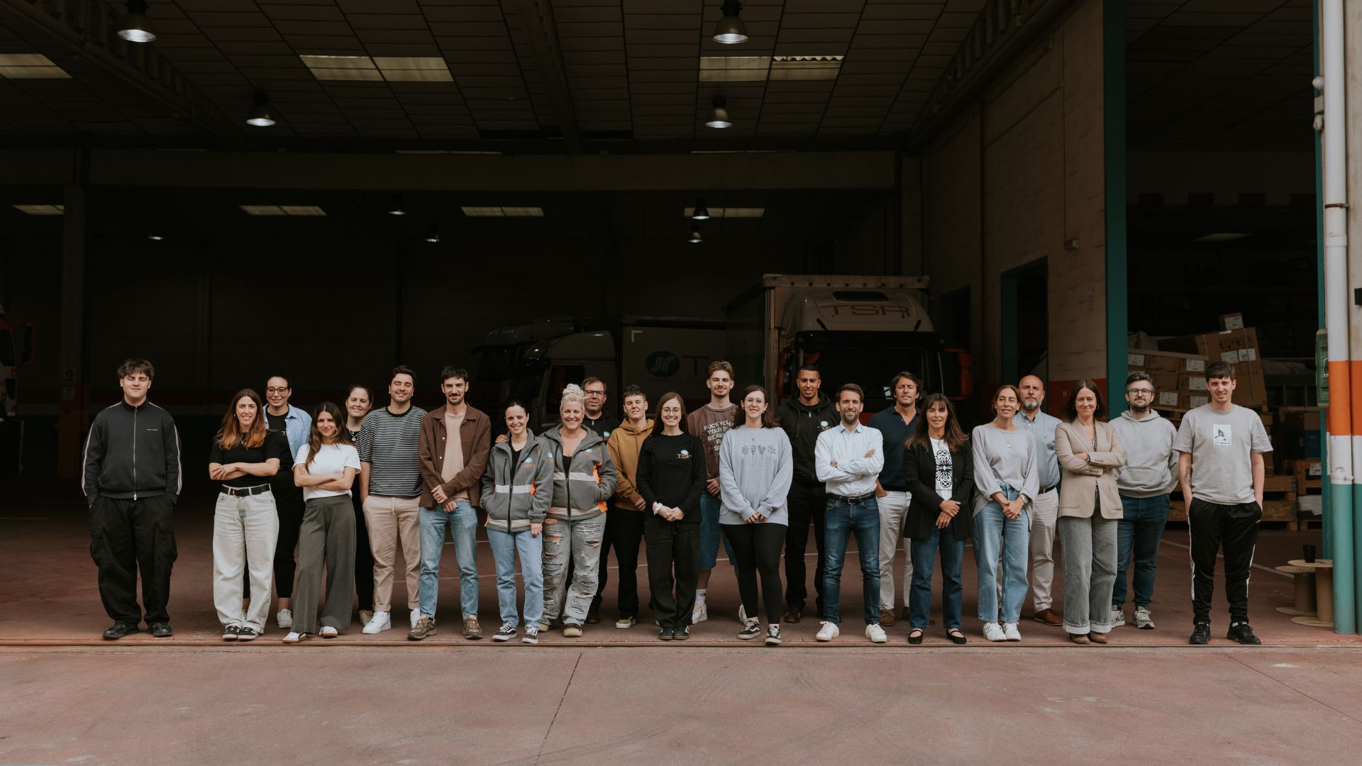 Equipo completo de TSR Group posando frente a un camión de la flota en las instalaciones logísticas de Bergondo
