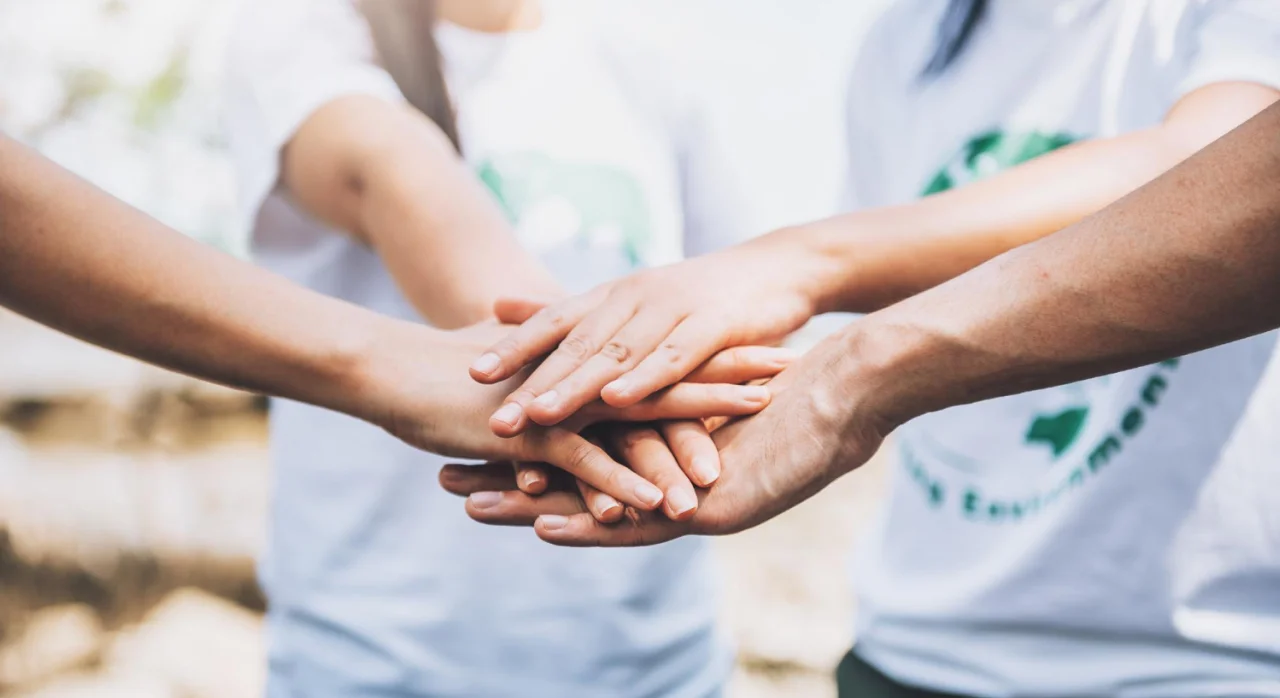 Several hands stacked together in a group gesture symbolizing unity and teamwork.
